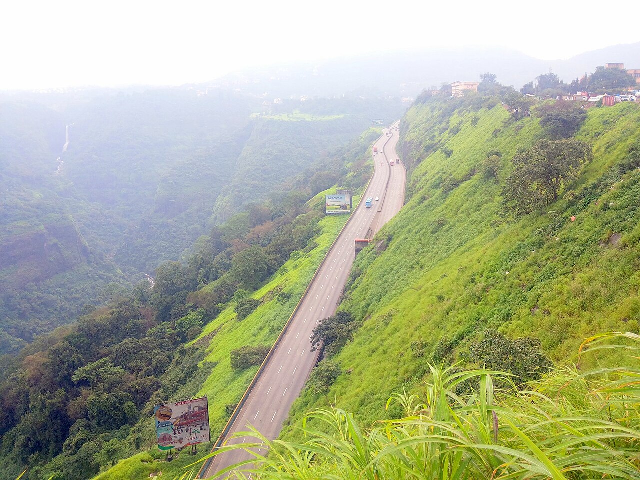 The expressway curving down through the green Khandala ghat in the monsoon, seen from a viewpoint above