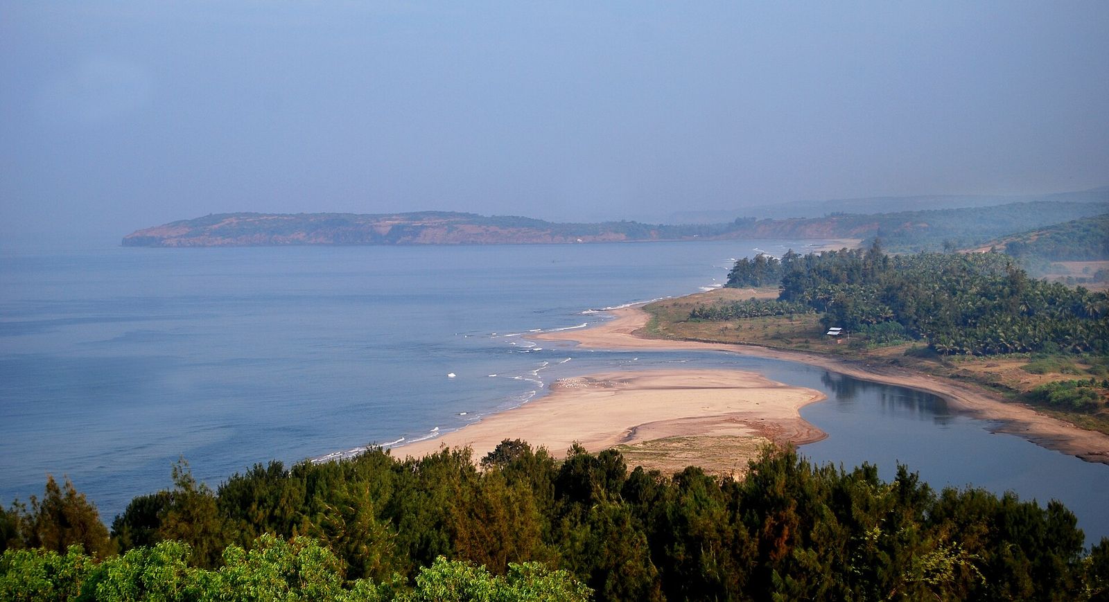 A curve of sand and a river mouth meeting the sea along the Konkan coast at Ganpatipule