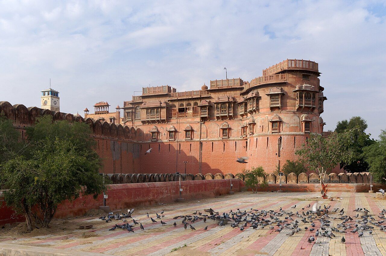 The red sandstone walls and balconies of Junagarh Fort in Bikaner, with pigeons on the courtyard in front
